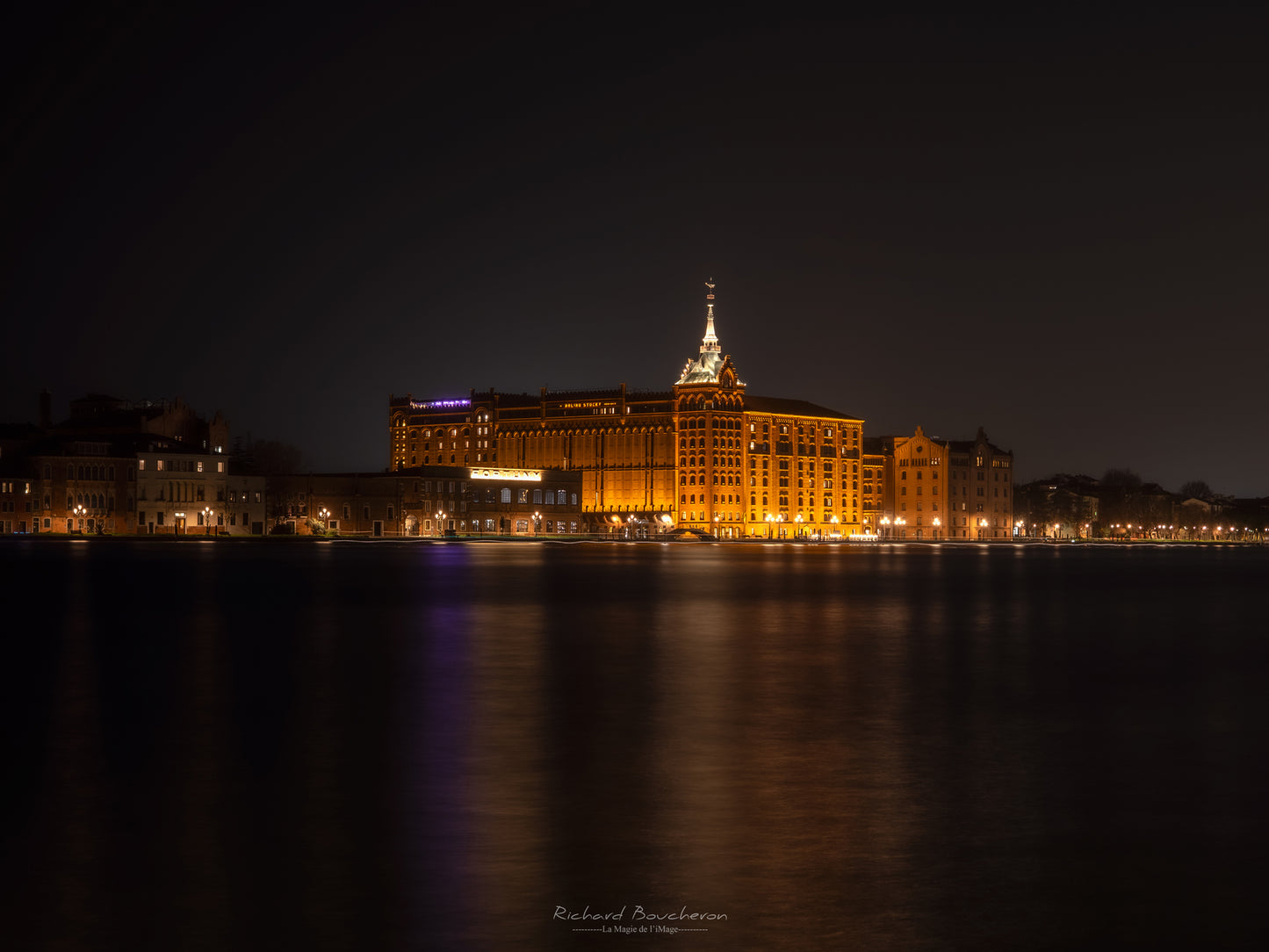 “Historic architecture illuminated at night – Reflections on the canal and serene atmosphere”