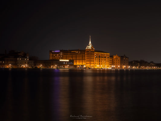 “Historic architecture illuminated at night – Reflections on the canal and serene atmosphere”
